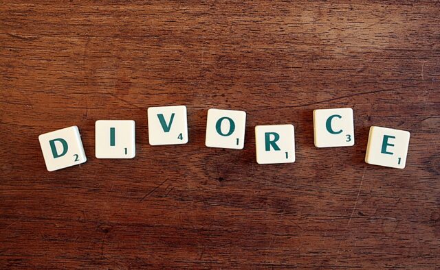 Scrabble tiles spelling the word "DIVORCE" are neatly arranged on a wooden surface, reminiscent of filing for divorce in New Jersey.