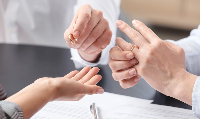 Young couple taking off wedding rings in lawyers office