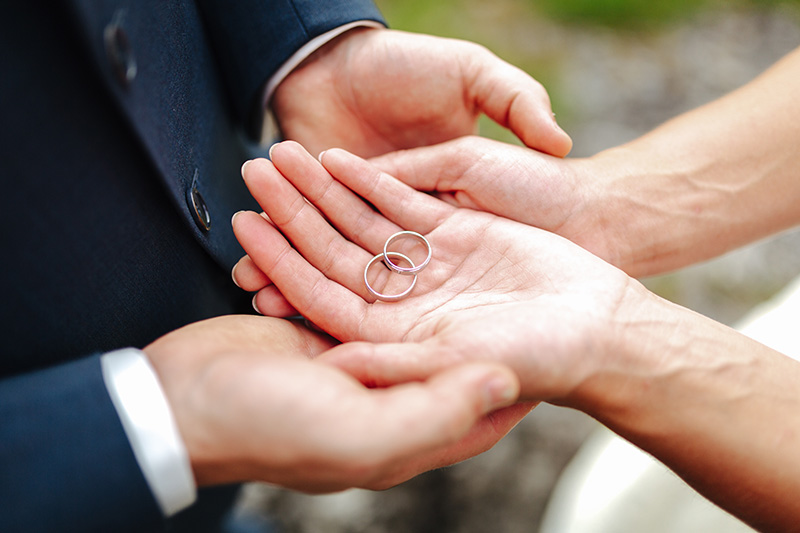 bride and groom holding wedding rings in their hands