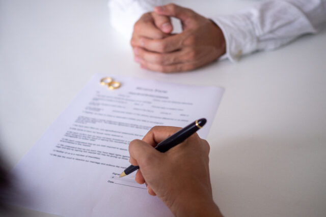 Hands of wife and husband signing decree of divorce, dissolution or canceling marriage or legal separation documents. filing divorce papers or premarital agreement prepared by lawyer.